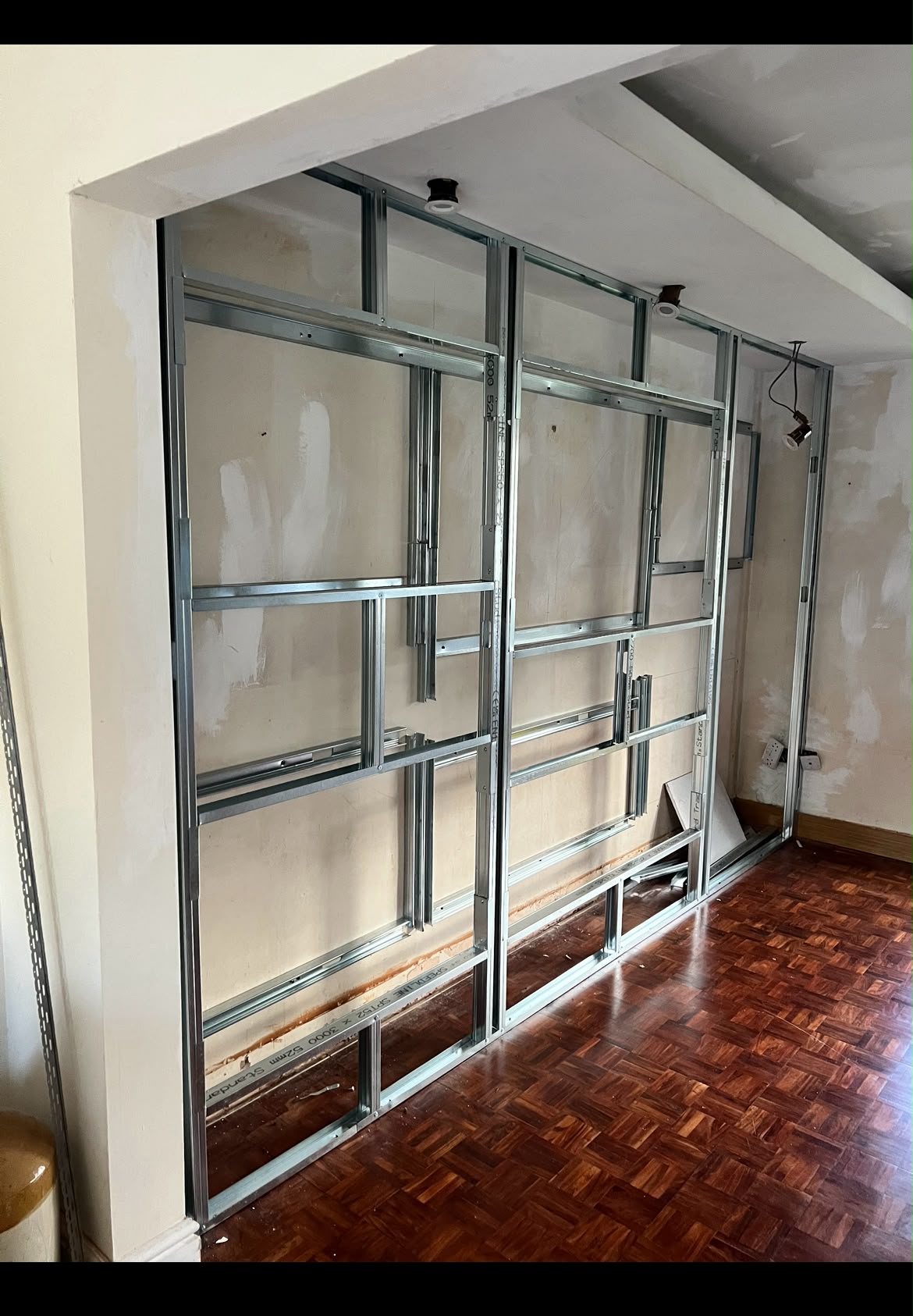 Interior room showing metal stud partition framing installed for a custom media wall or room divider.