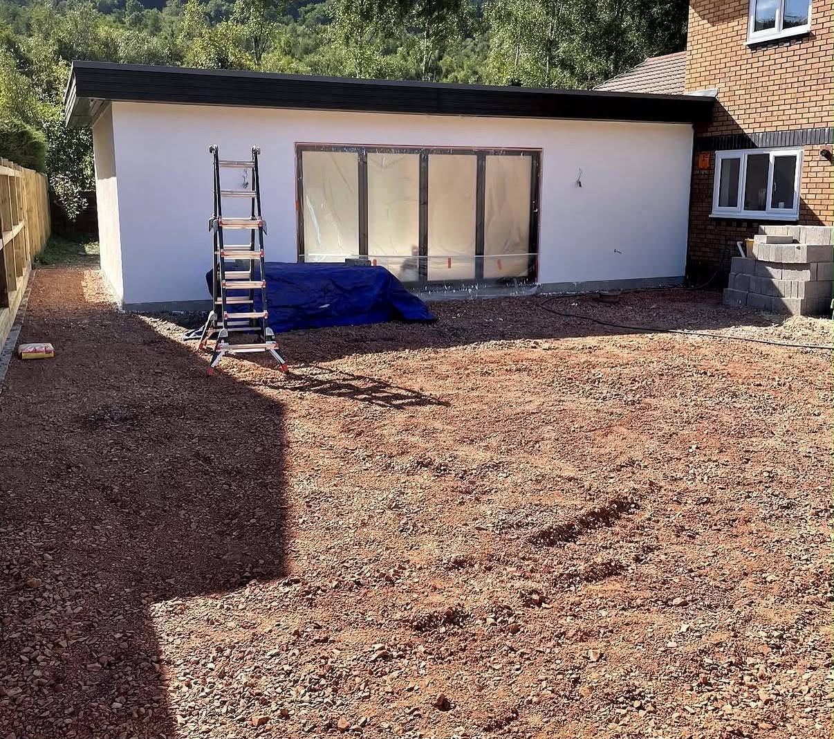 Finished white silicone render on a garden room extension with dark grey bi-fold doors