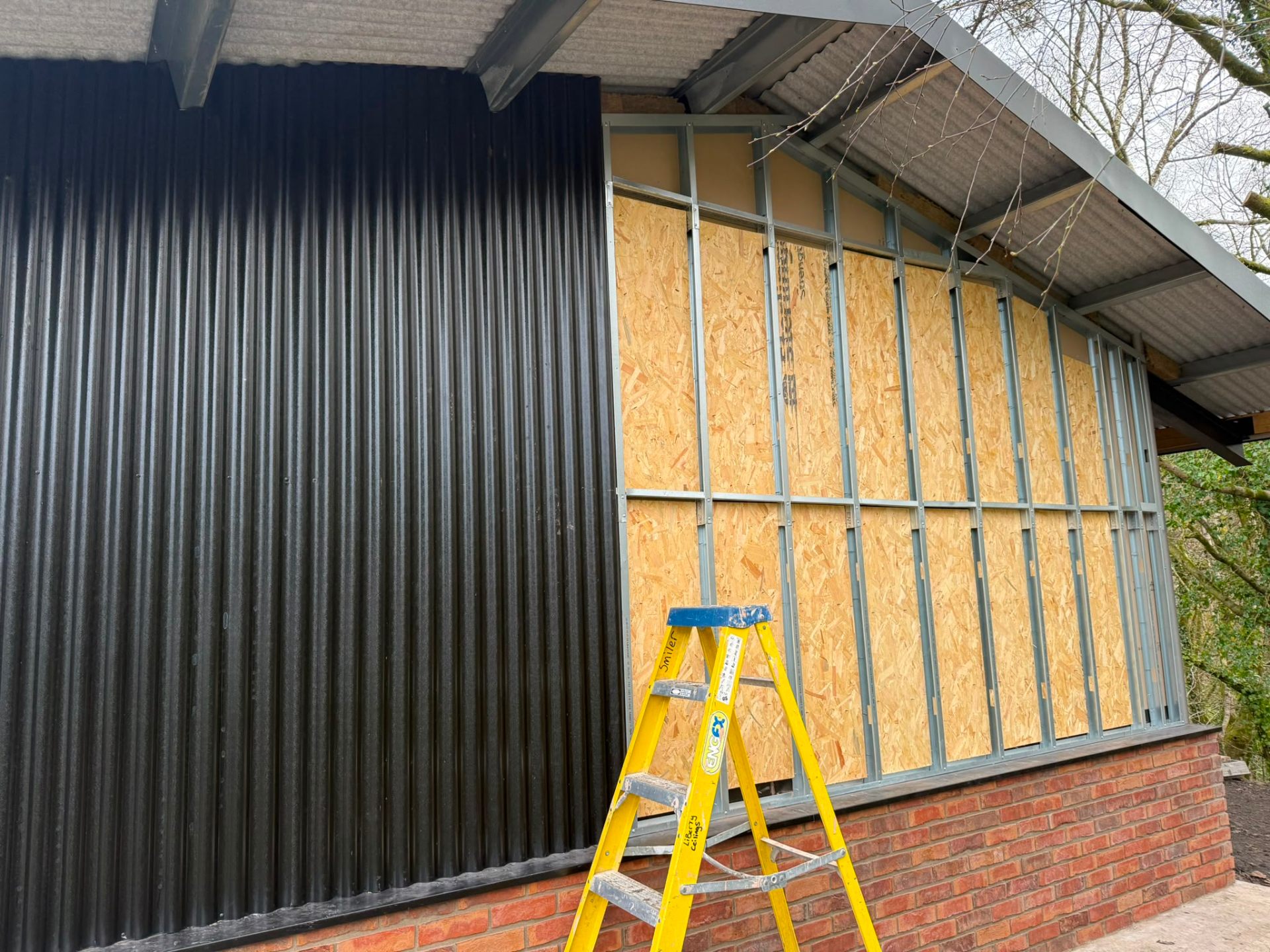 Sheet cladding and OSB boarding being installed on an outbuilding exterior wall.