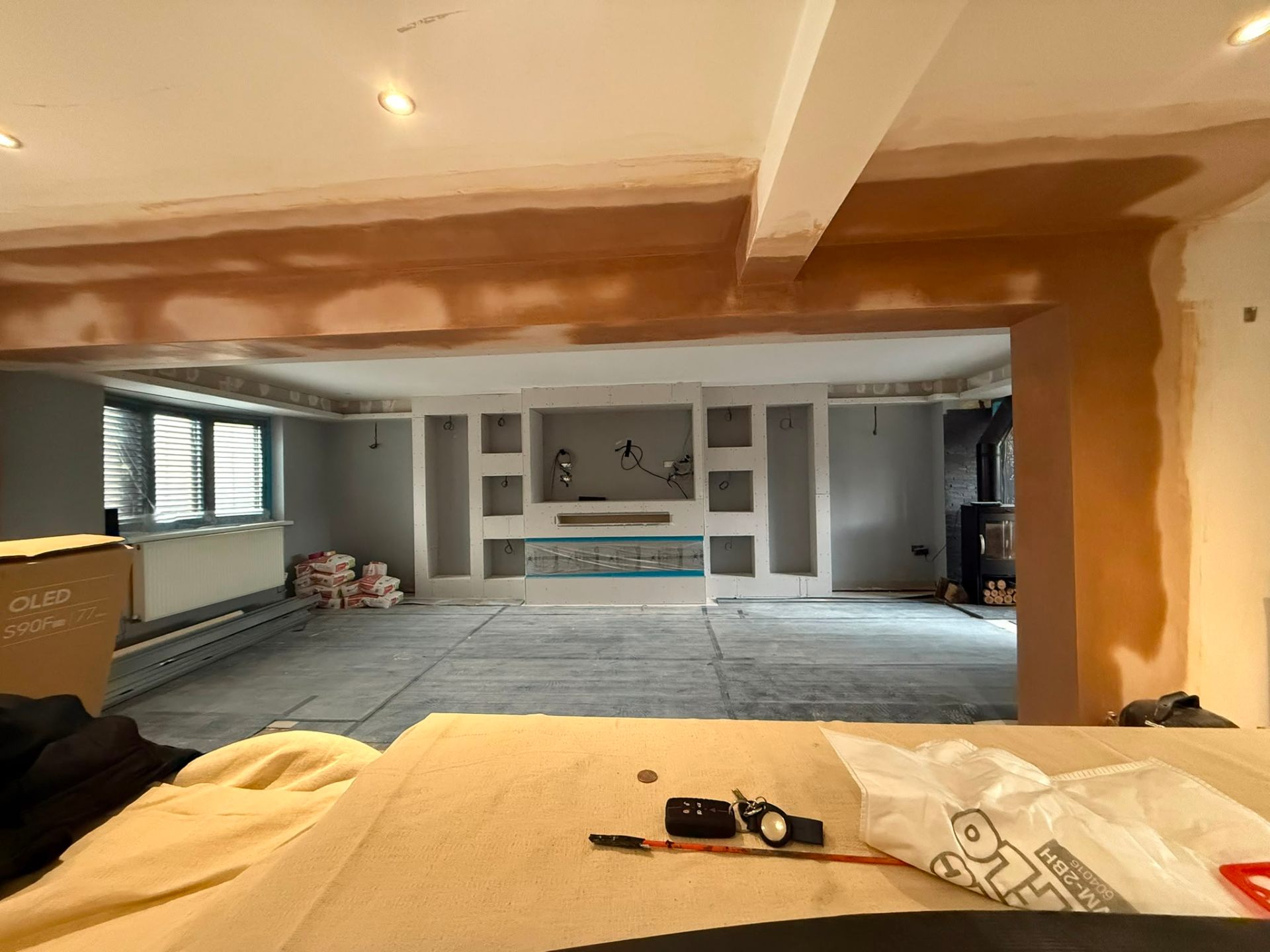 Large interior room undergoing renovation showing drywall framing for a bespoke media wall unit.