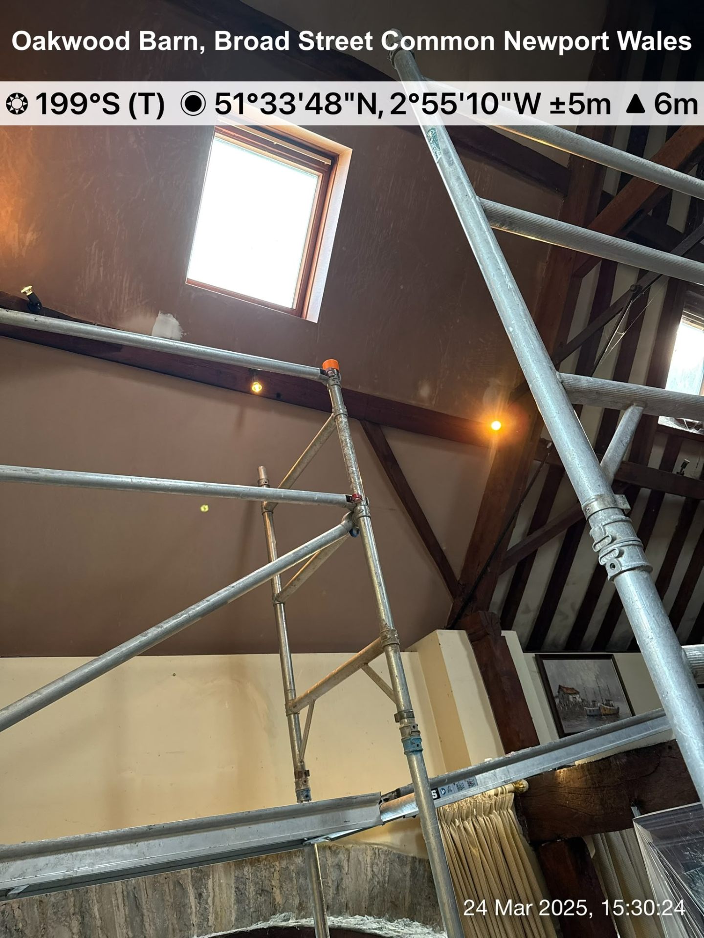Interior barn ceiling renovation featuring timber beams, a skylight, and metal scaffolding for access.