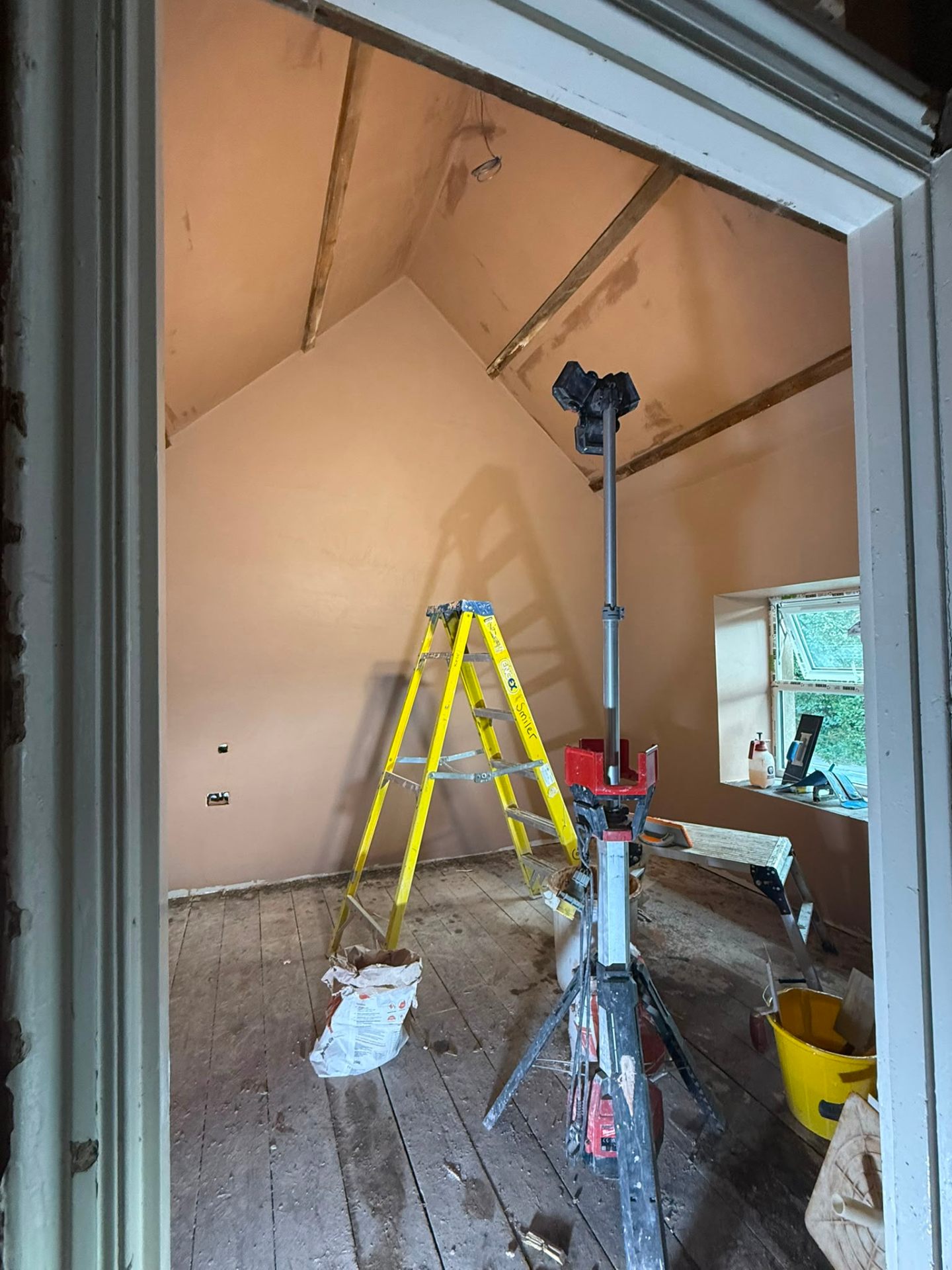 Interior room with freshly plastered pink skimming on vaulted ceiling and walls including site equipment.