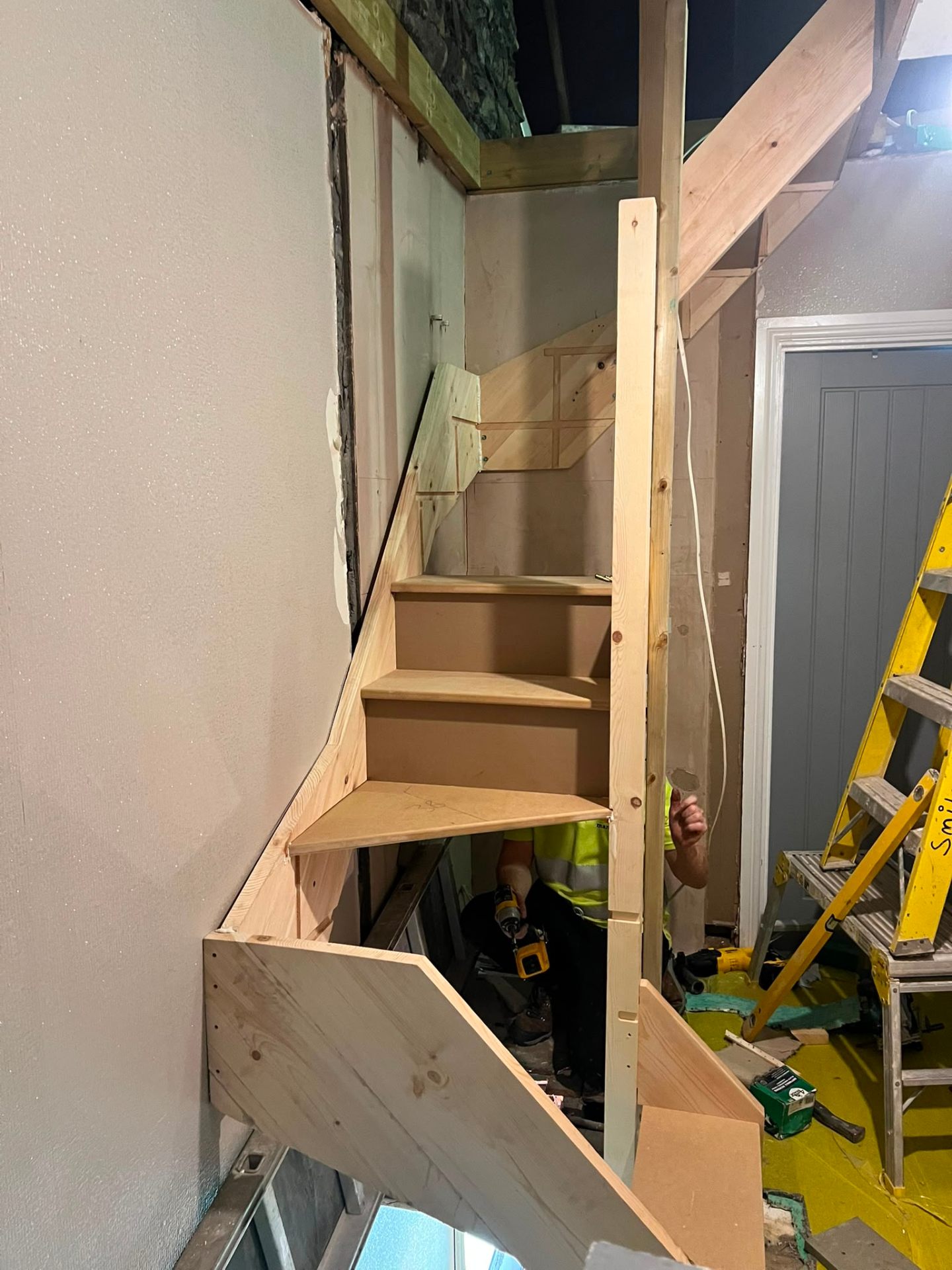 Professional joiner constructing a bespoke timber staircase for an attic conversion project interior.