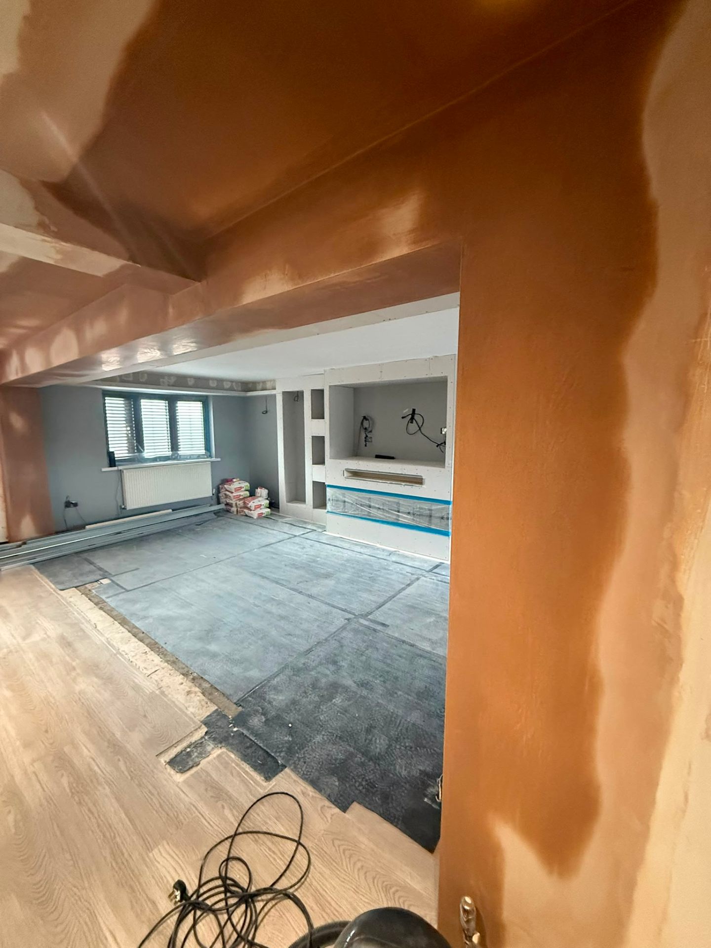 Interior room with freshly applied wet brown plaster on structural beams and walls.