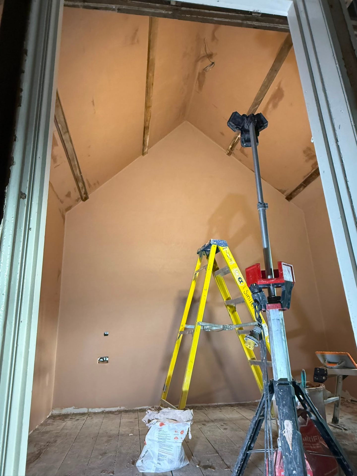 Low angle view of freshly plastered vaulted ceiling and gable end wall with site equipment.