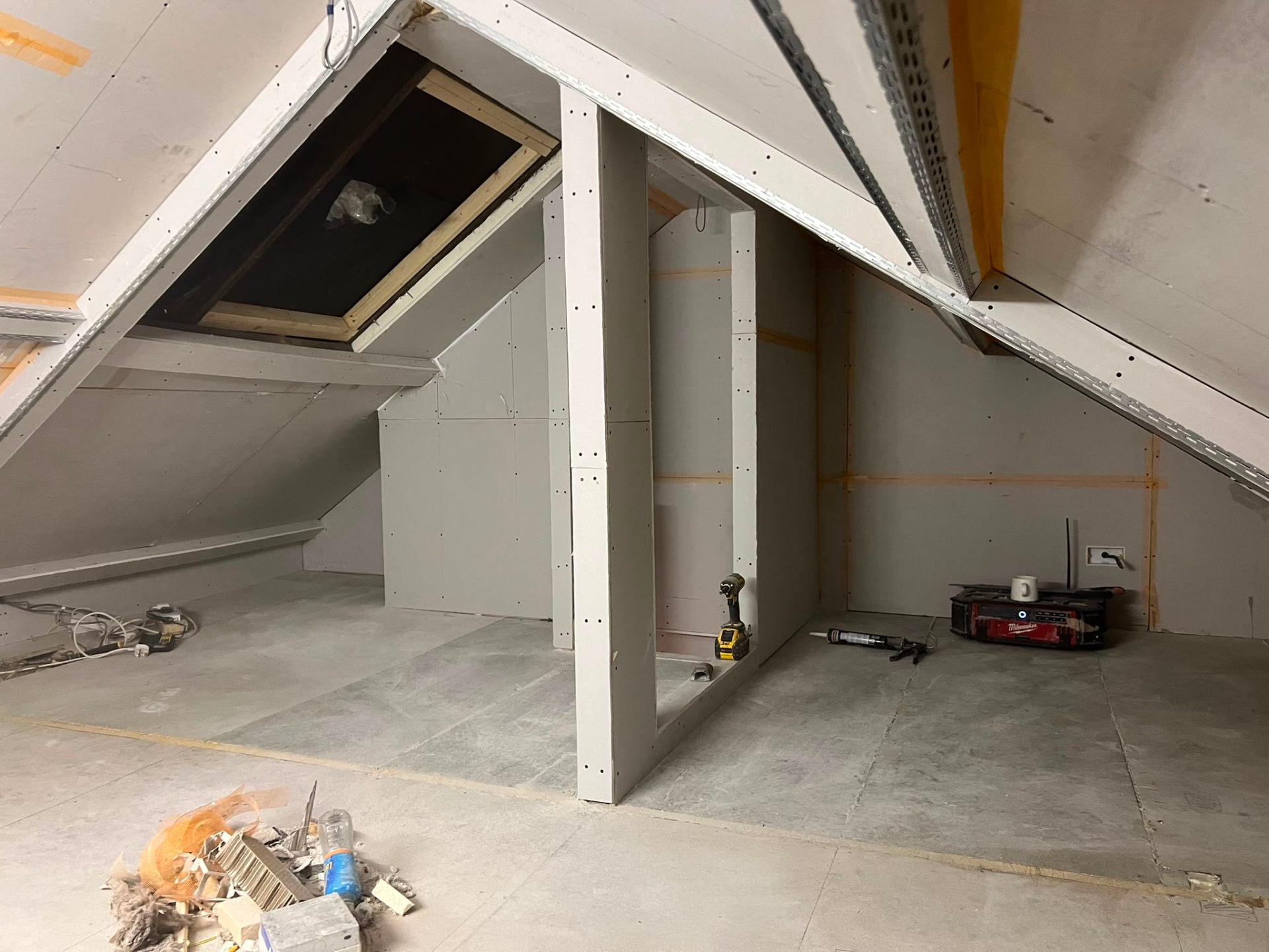 Professional attic conversion in progress with plasterboard installed on sloped ceilings and partition walls.