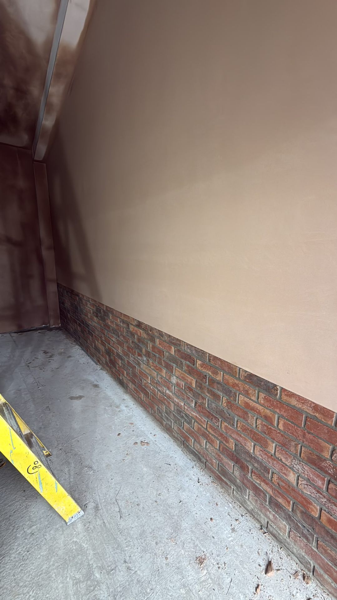 Smooth plaster finish on the upper wall above a decorative brick base in an interior room