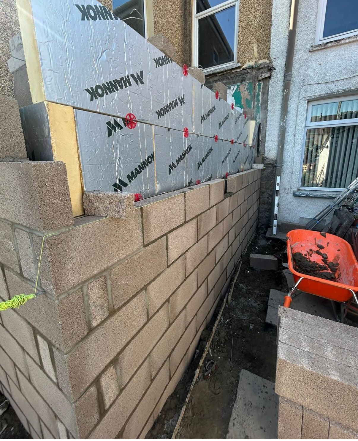 Side extension build showing insulated cavity wall construction and fresh blockwork during the early build stage.